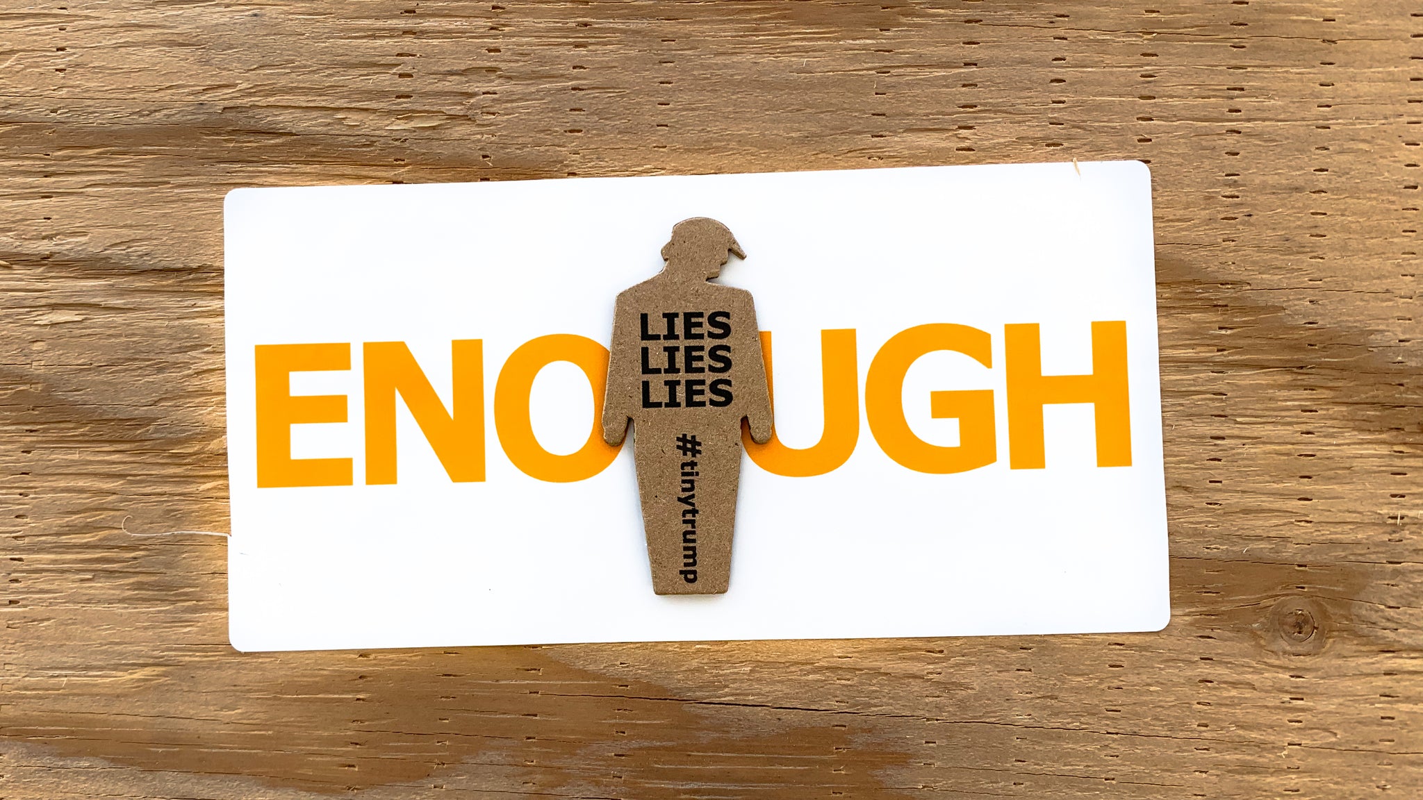 "ENOUGH" tiny trump sticker measuring 3.75" x 3.5" shown with a "Lies Lies Lies" tiny trump stuck in the middle; both are mounted on a piece of plywood