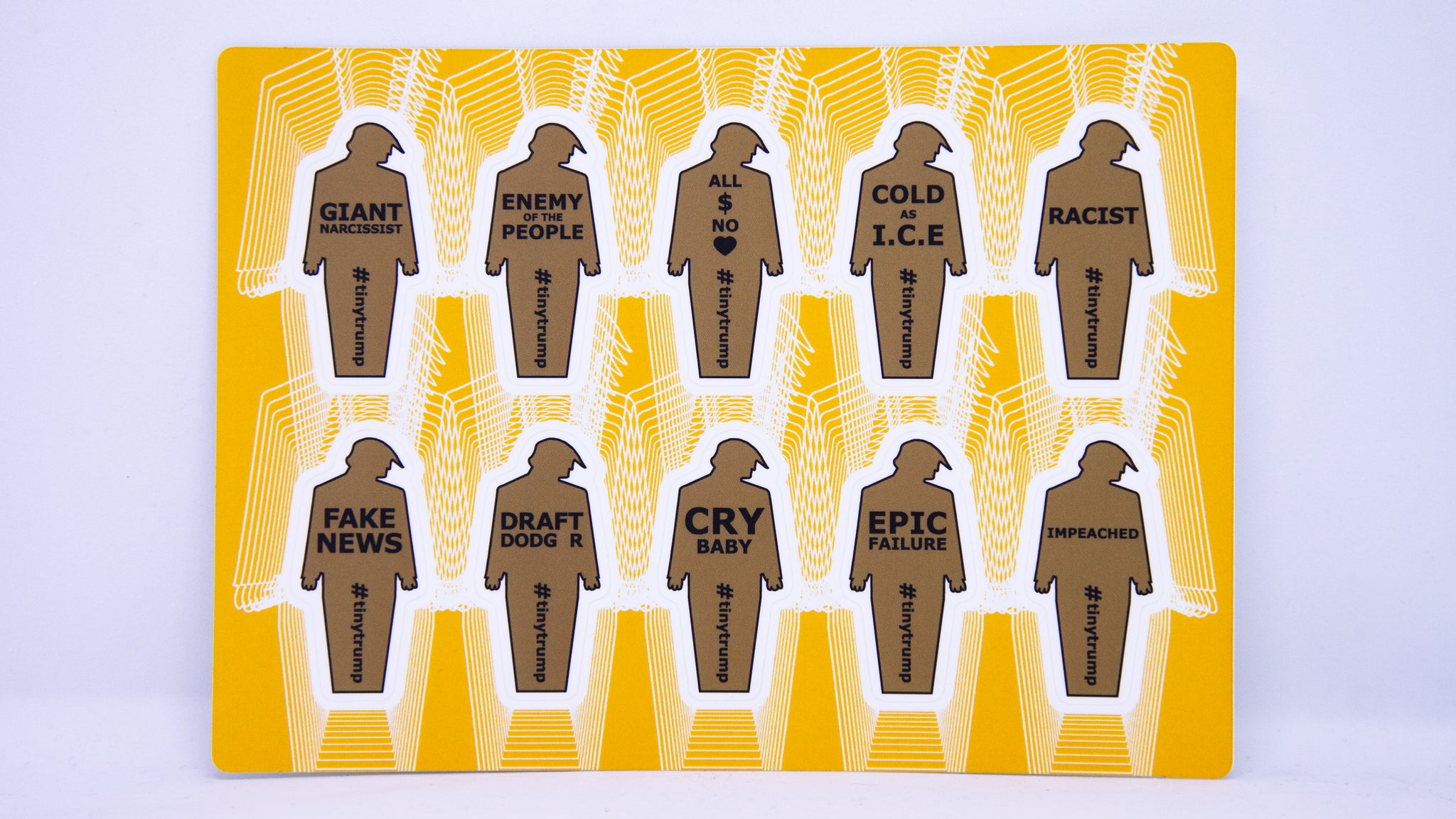 A sticker sheet with 10, two inch tall tiny trumps with the following slogans: Giant Narcissist, Enemy of the People, All $ no Heart, Cold as I.C.E, Racist, Fake News, Draft Dodger, Cry Baby, Epic Failure, Impeached