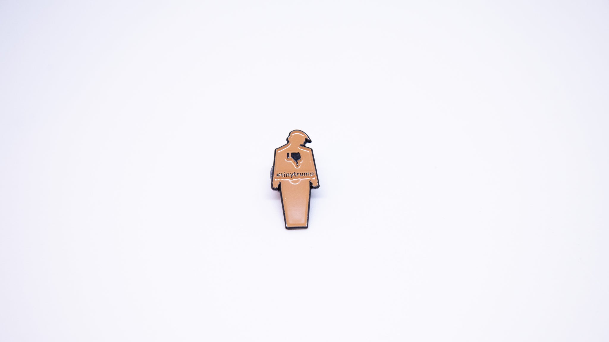 Close up shot of a 1.5" tiny trump enamel pin shown with a thumbs down sign