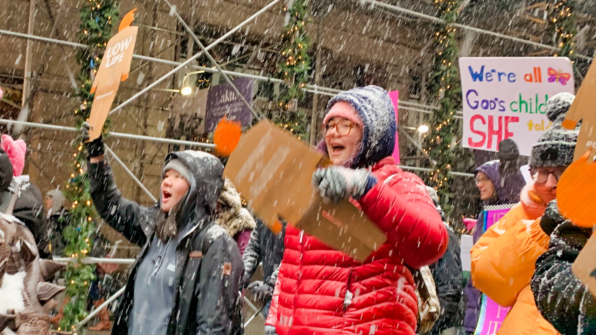 Two protesters marching in the snow, each holding their own two foot tall, cardboard tiny trumps, at the Women's March in New York City