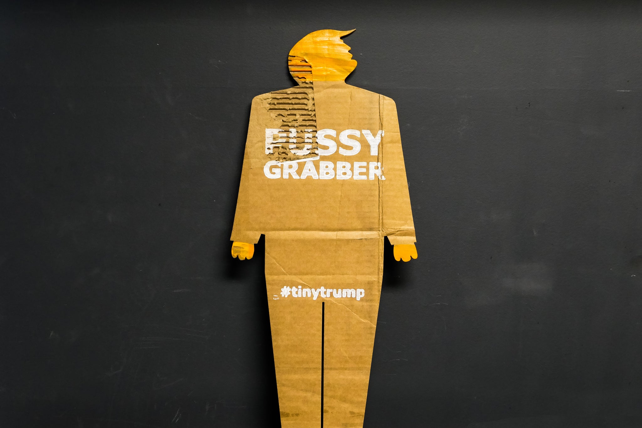 A two foot tall, cardboard tiny trump with the slogan "Pussy Grabber"