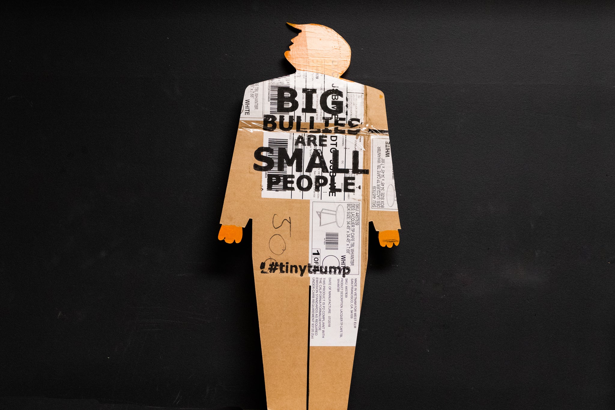 A two foot tall, cardboard tiny trump with the slogan "Big Bullies Are Small People"