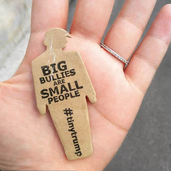 tiny trump with the slogan "Big Bullies Are Small People" shown in the palm of someone's hand